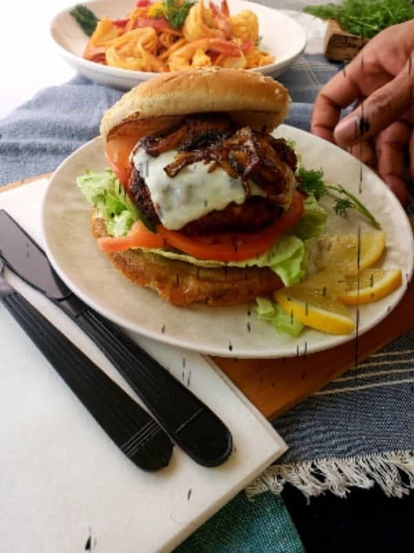 A Soul Cuisine Cafe plated sandwich with fried fish, lettuce and tomato, served with a side of shrimp pasta
